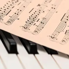 Partytura muzyczna leży na klawiaturze fortepianu. Widać nuty i cyfry, jakby ktoś przygotowywał się do zagrania "alleluja".