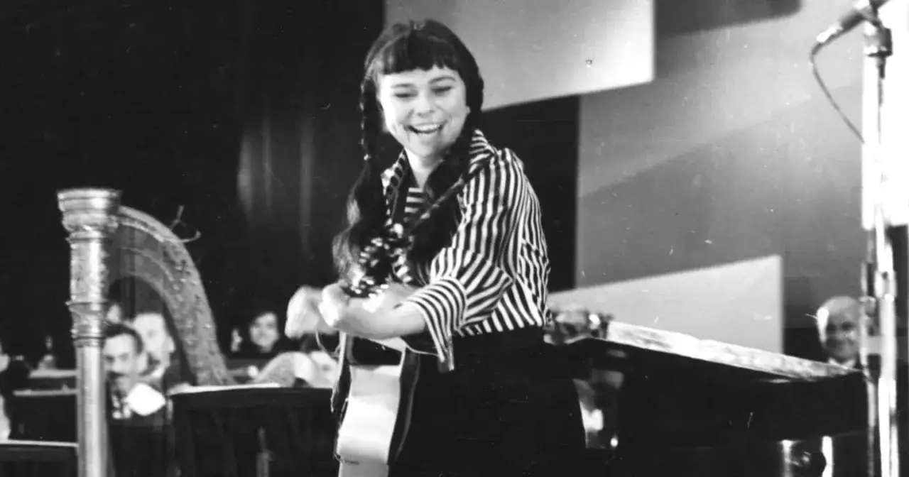 Karin Stanek śpiewa, grając na gitarze. W tle harfa i publiczność. Jej utwory poruszały serca.