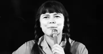 Karin Stanek z mikrofonem, warkocze i charakterystyczna grzywka. Jej niezapomniane utwory wciąż brzmią w sercach fanów.